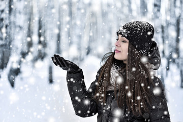 Girl with dark long hair in the winter park in snowfall