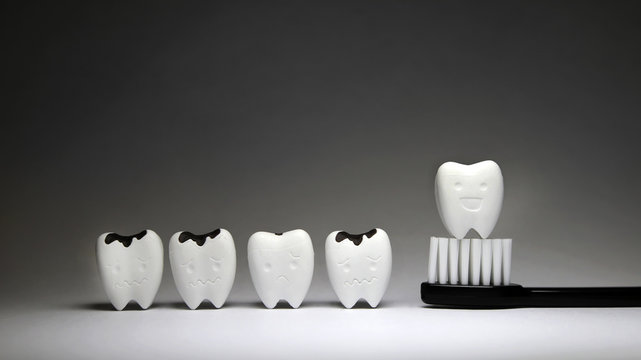 Decayed tooth and Tooth model in happy emotion on black toothbrush, if brush the teeth, teeth will good healthy 
