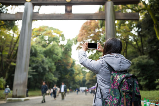 Woman take photo of Japanese torri in Meji Shrine
