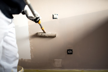 Handy man decorating walls with paint. Construction plaster worker painting and renovating with professional tools - Powered by Adobe