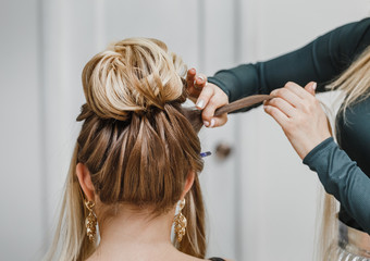 Fototapeta premium Hairdresser makes complex and beautiful hairstyle upper bun. Suitable for evening and wedding style