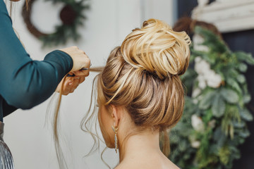 Hairdresser makes complex and beautiful hairstyle upper bun. Suitable for evening and wedding style - obrazy, fototapety, plakaty