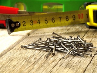 a bunch of nails in front of carpentry tools, shallow depth of field, macro