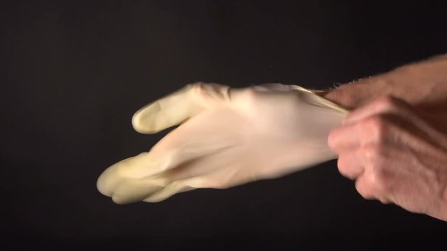 On hand wear disposable rubber glove on a black background