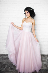 beautiful young brunette woman in a light pink long dress