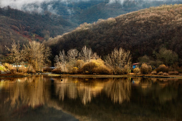Trees and mountains reflected in the water of the reservoir of the village called Rioseco in the north of Spain