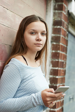 Teenage Girl Texting On Mobile Phone In Urban Setting