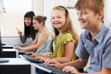 Female Elementary Pupil In Computer Class With Teacher