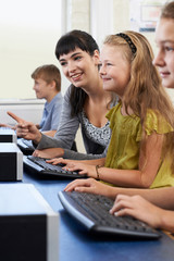 Female Elementary Pupil In Computer Class With Teacher