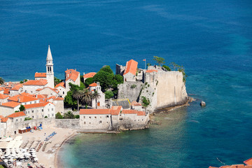 The Old Town and fortress are on peninsula in Adriatic sea. Urban beach the Ricardova Glava. Aerial view. Budva, Montenegro, Europe