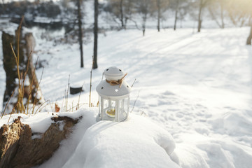 Flashlight inside burning candle standing in snow in winter