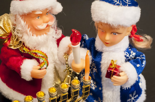 Toys Ded Moroz (Santa Claus) and Snegurochka lighting hanukkah candles. In December 2016 Jewish holiday Hanukkah coincides with Christmas and New Year. 