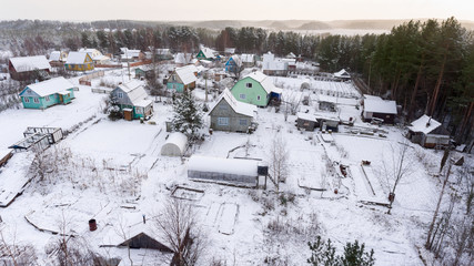 Timber houses and barns are covered with snow. Small agriculture earth lots are in coniferous wood. Karelia, Russia