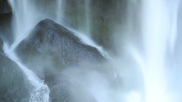 Close up footage of water falling on black rocks at Misol Ha waterfall in Mexico in high definition footage with ambient audio
