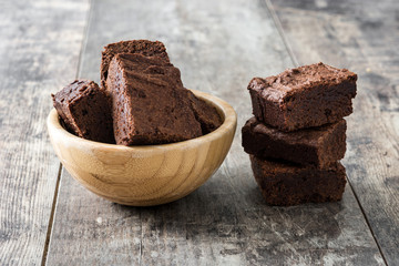 Chocolate brownie portions in bowl on wooden background
