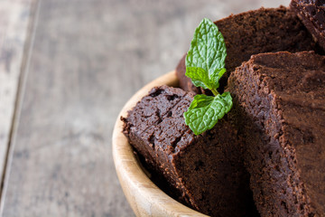 Chocolate brownie portions in bowl on wooden background
