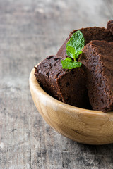 Chocolate brownie portions in bowl on wooden background
