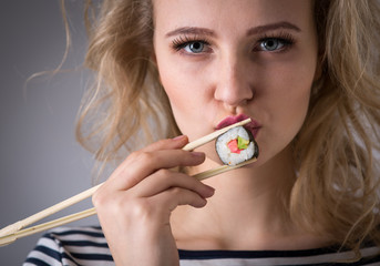 Young woman holding sushi rolls