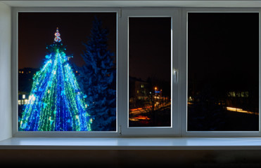 Playground with glowing figures next to a large decorated Christmas tree lights outside the window