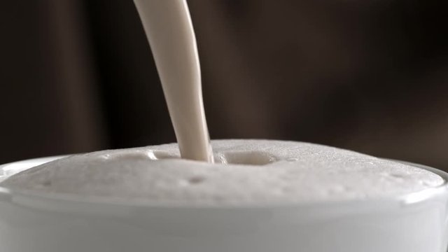 Pouring latte cappuccino cup in slow motion
