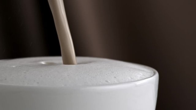Pouring latte cappuccino cup in slow motion