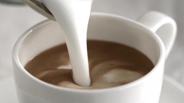 Pouring latte cappuccino cup in slow motion