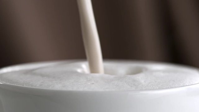 Pouring latte cappuccino cup in slow motion