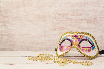 Mardi gras mask and beads for party on wooden background
