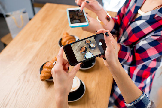 Photographing with smart phone coffee with croissants