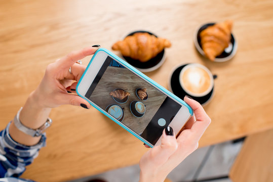 Photographing with smart phone coffee with croissants