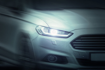 Fototapeta premium White sport car ride on road motion blur. Xenon and angel eyes headlamps