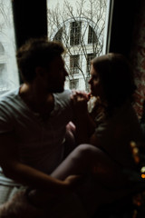 Naklejka premium Happy couple of lovers in pajamas sit on the windowsill. Christmas atmosphere.