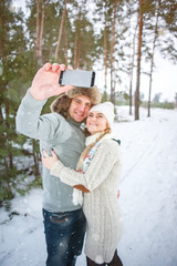 A couple on a walk in the woods in the snow, making selfie on smartphone