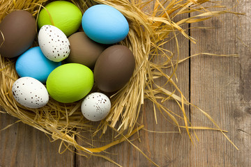 Easter eggs on wooden background in the nest. Top view