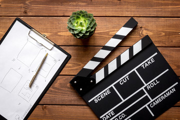 Screenwriter desktop with movie clapper board wooden background top view