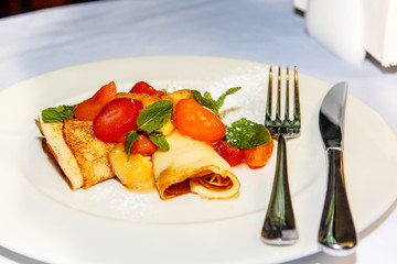 Pancakes sprinkled with powdered sugar fruit and berries are on