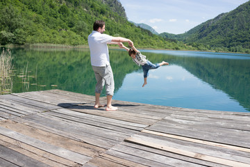 Fototapeta na wymiar Dad and son playing on the mountain lake