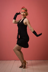 Fototapeta premium Pretty actress in black retro dress dancing charleston
