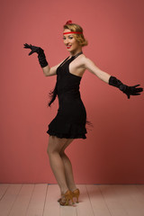 Fototapeta premium Pretty actress in black retro dress dancing charleston