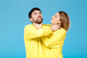 Fototapeta premium Young beautiful couple smohering each other over blue background.