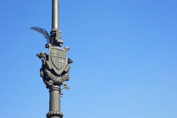 Coat of arms of City of Barcelona, Spain, made of iron and filled with florid elements. This ornament decorates some street lamp outdoors