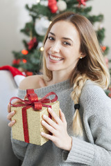 Beautiful woman with christmas box gift in front of Christmas tree