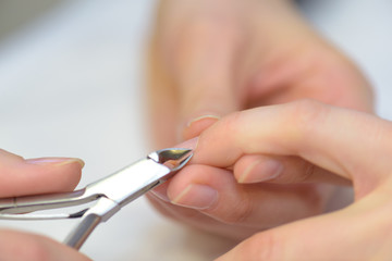 Tweezers being used on a woman's fingernail