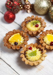Homemade desserts with fruits for the new year. Desserts for the holidays. View from above. Christmas decorations and toys. The desserts on the wooden background.