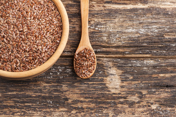 Wooden bowl and flax seed on wooden background