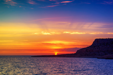 Beautiful colorful sunset at the sea with dramatic clouds and sun shining