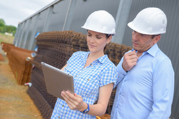 Two workers in hardhats looking at tablet