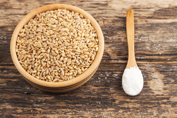 Wooden bowl and wheat grain on wooden background