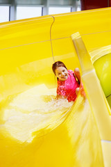 Young girl laughs sliding around the corner of a water slide