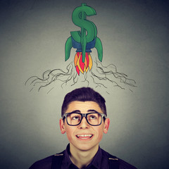 man in glasses looking up at rocket dollar sign above head